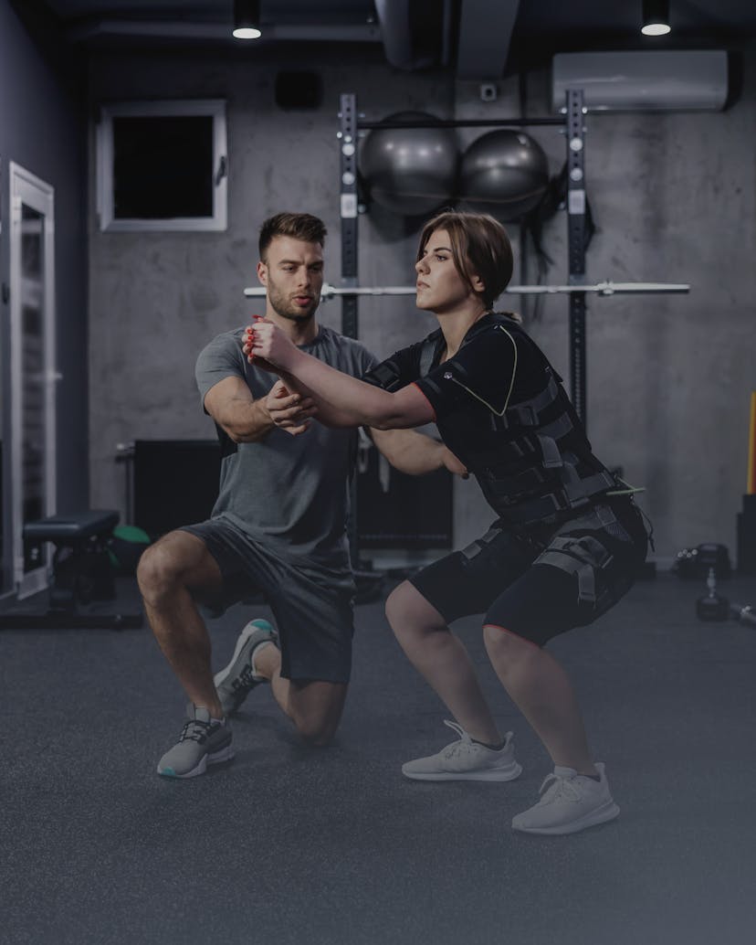 instructor assists performing stability squats