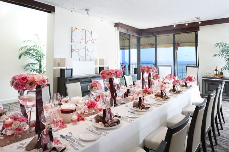 Reception room with long table filled with pink and white roses