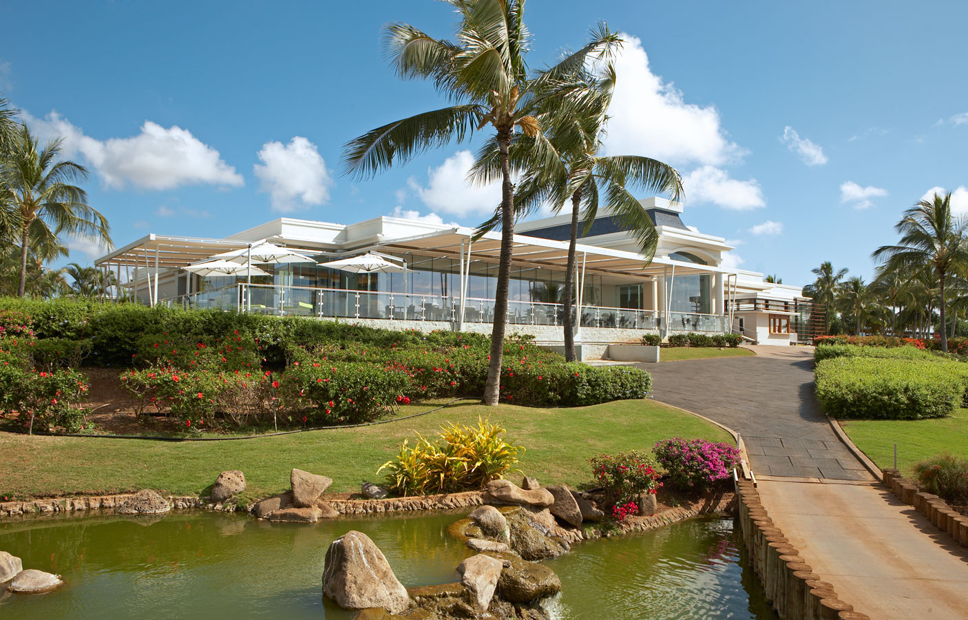 Wide-angle photo of clubhouse with lawn and pond in view