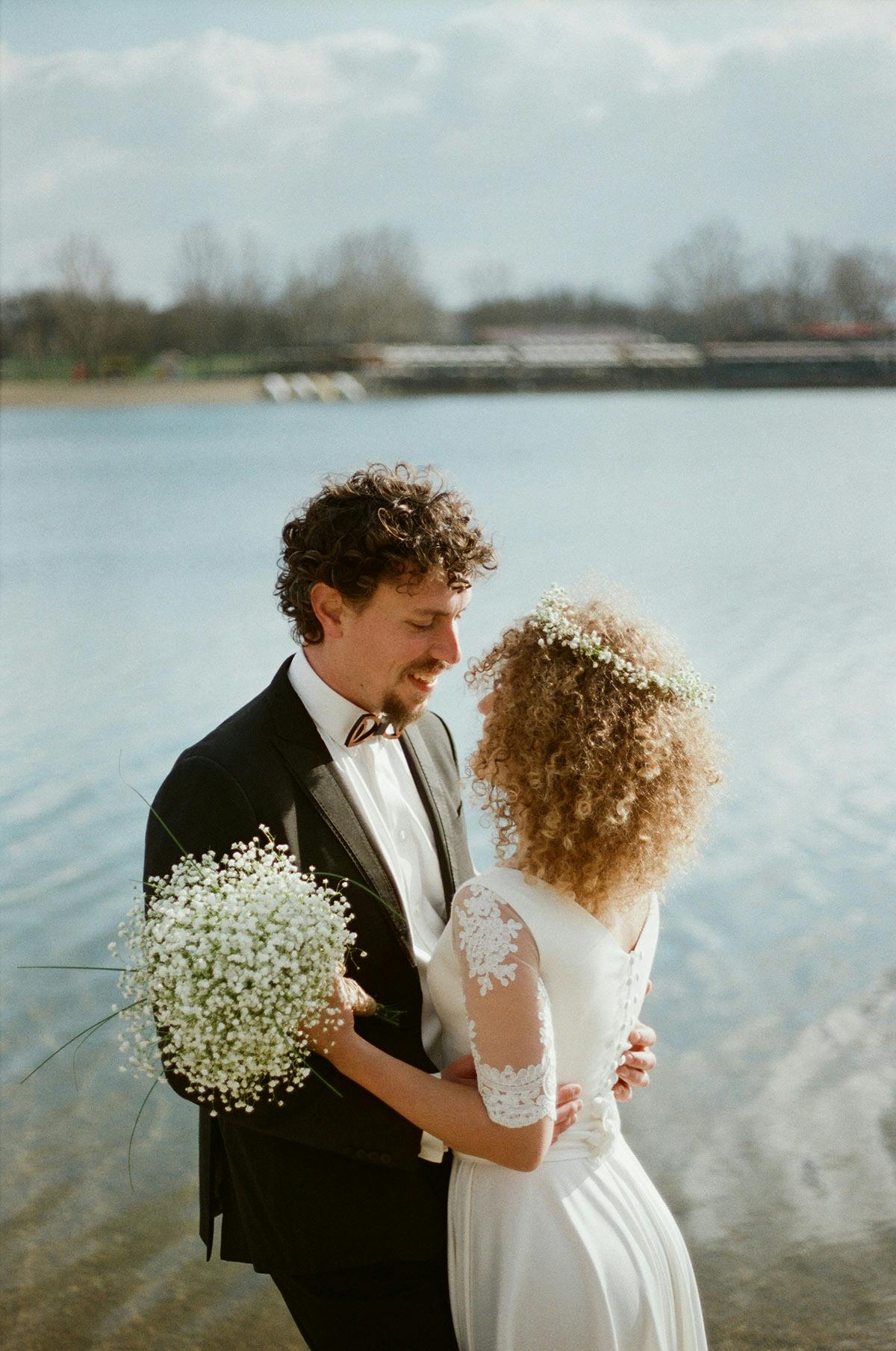 Film wedding photography couple by lake bride holding bouquet