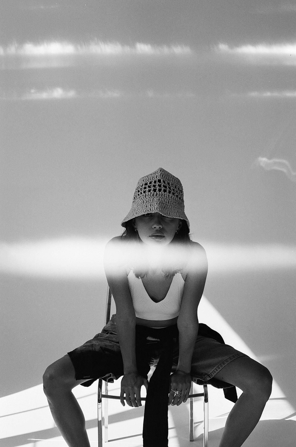 Film photography young woman in bucket hat on a chair with directional light