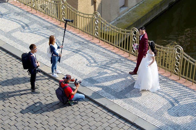 Professional wedding photographer capturing a bride and groom on a bridge near a river