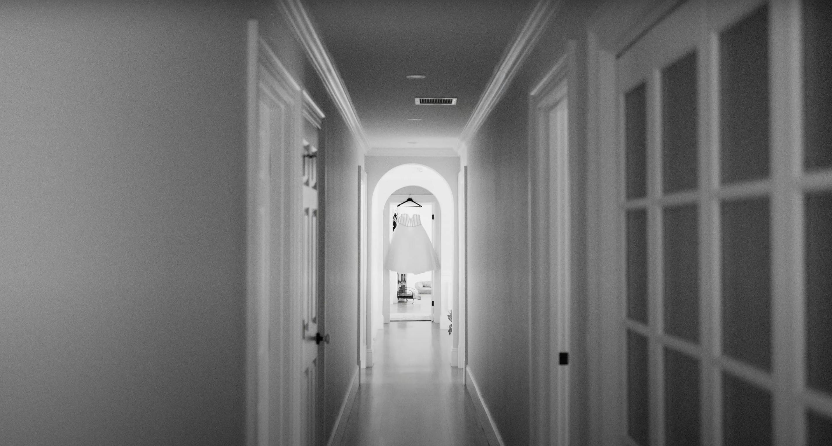 Adonye Jaja black and white photograph of a wedding dress hanging in a hallway