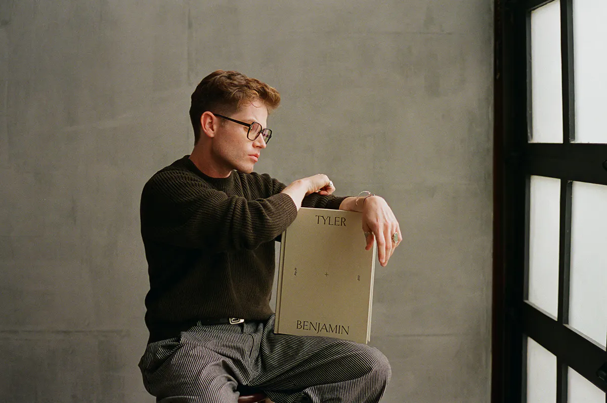 Man holding a Vision Art linen wedding album debossed with the names Tyler and Benjamin in a studio with concrete walls