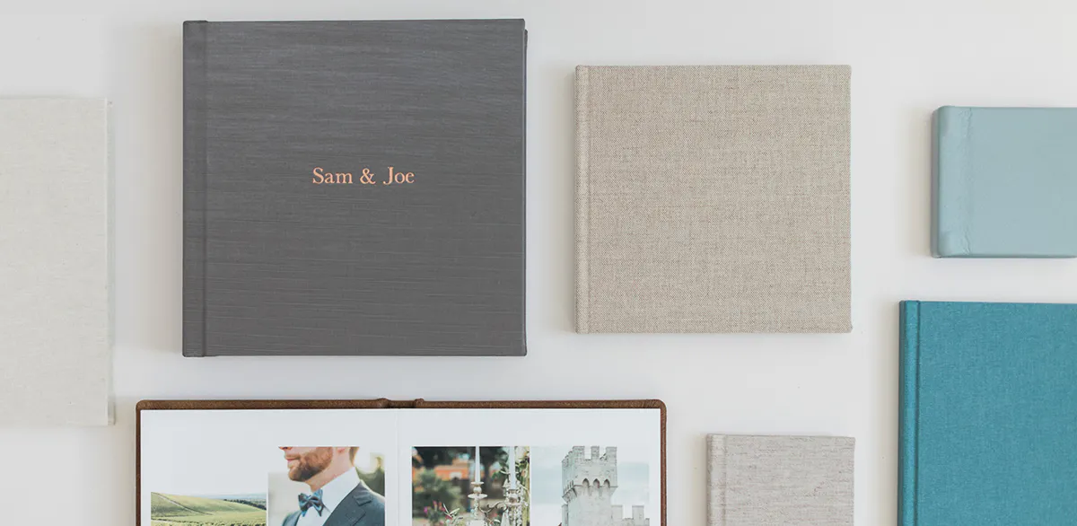 Flat lay of Kiss Books album covers in linen, silk, and leather with one open wedding spread.