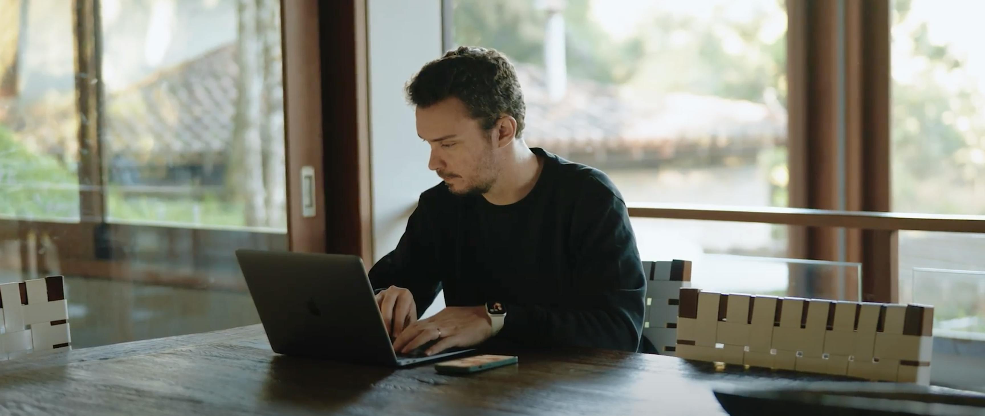 Celso Modeneze sentado ao laptop enquanto desenha álbuns em SmartAlbums