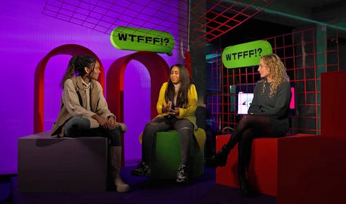 Drie jonge vrouwen met elkaar in gesprek in het decor van WTFFF!?
