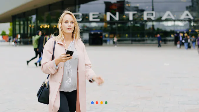Vrouw met telefoon in haar handen voor station Rotterdam Centraal 
