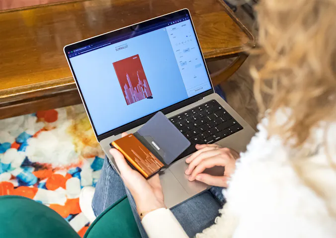 A lady behind her laptop designing her own wallet .