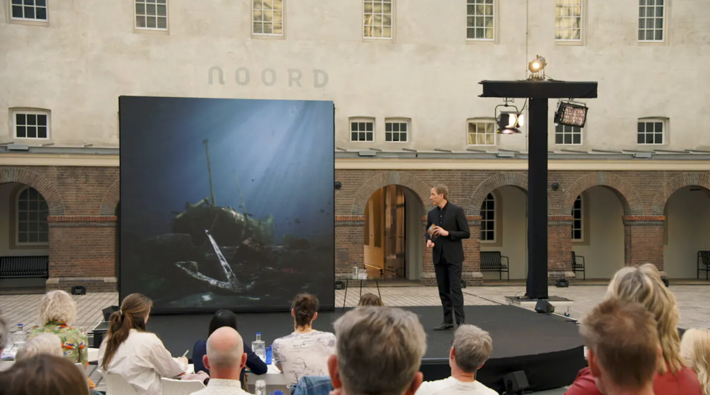 A full auditorium with Pieter Roelofs from the Rijksmuseum on stage.