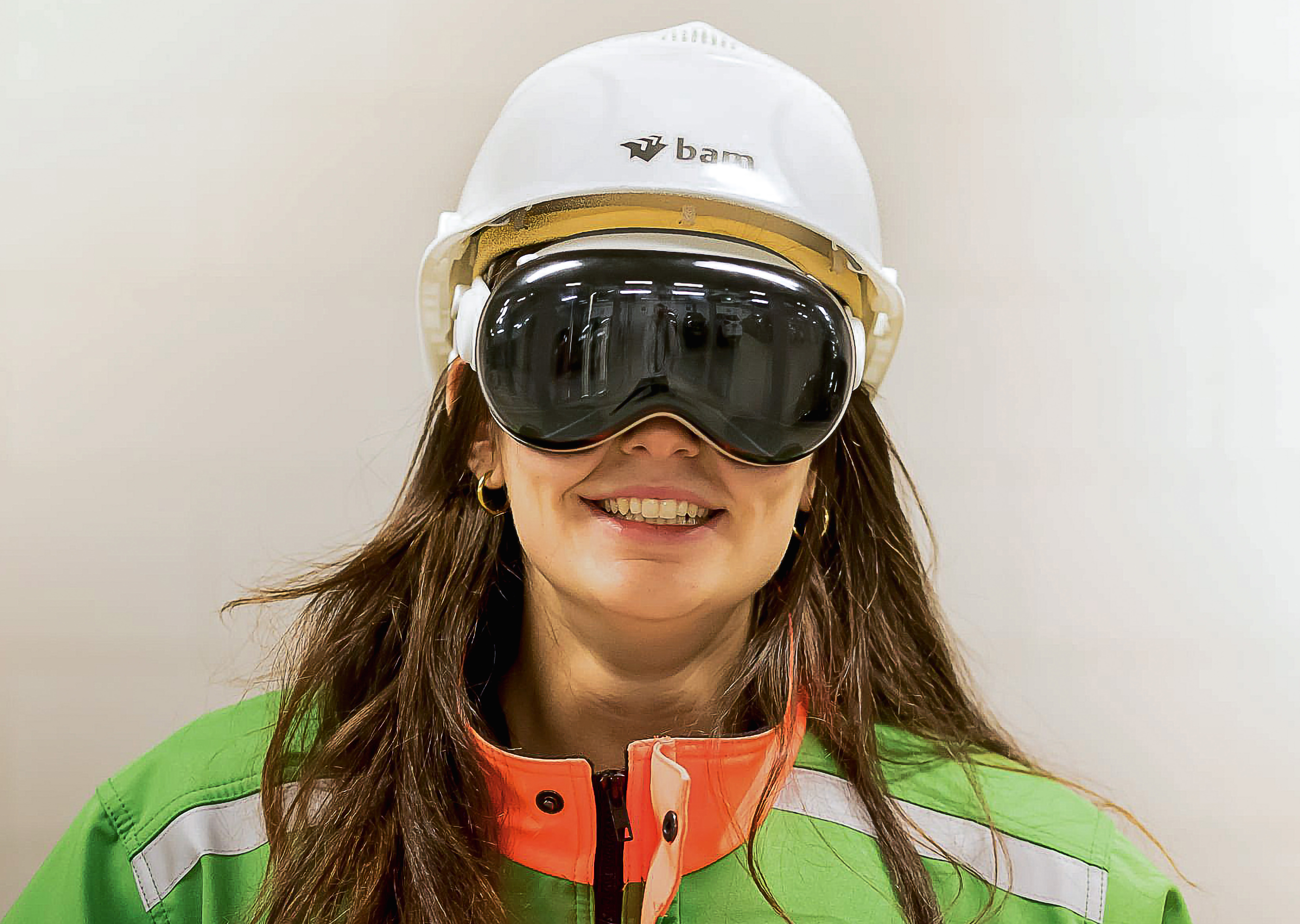 Een dame in bouwkleding van BAM, ze kijkt de camera in en heeft de Apple Vision Pro bril op haar hoofd.
