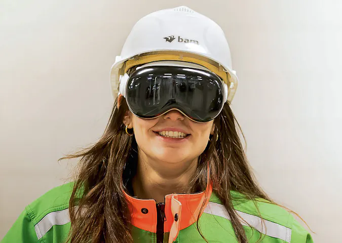 A woman in BAM construction attire, looking into the camera with the Apple Vision Pro headset on her head.