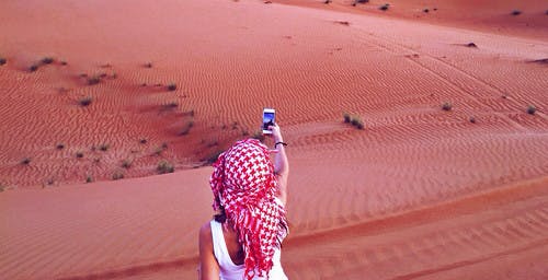 Meisje met mobieltje in woestijn van het Midden-Oosten