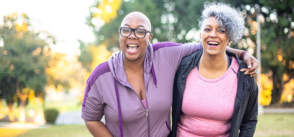 Two women smiling and embracing outside