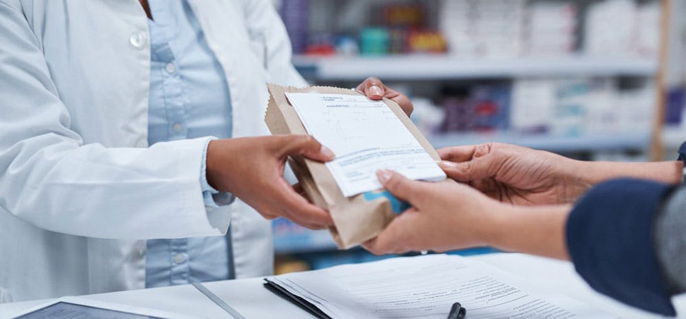 Pharmacist handing drugs to consumer