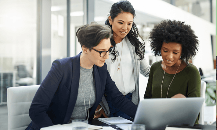 three women gathered around a laptop computer