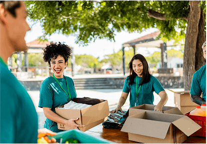 two women and a man carrying boxes during a volunteer event
