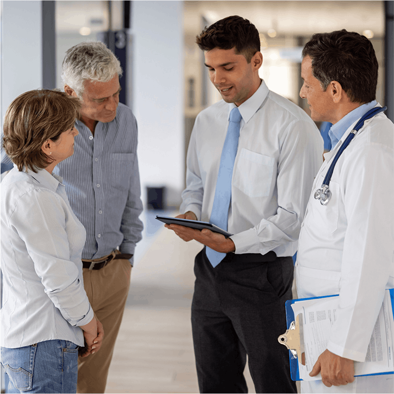 elderly couple having a doctor and man in suit explain over an ipad