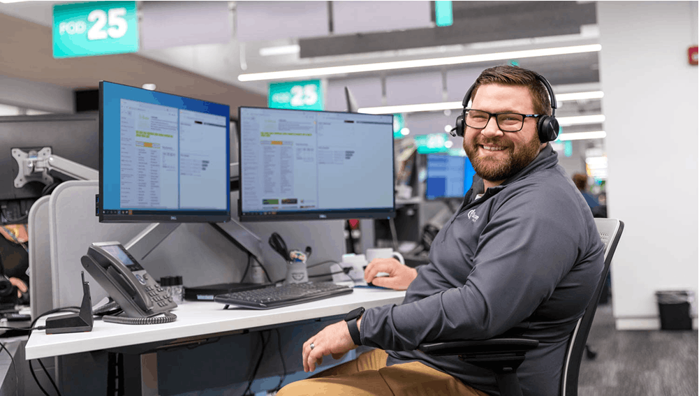 Smiling man at computers looking at camera