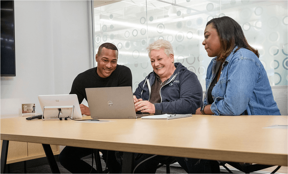 3 employees looking at a computer in a meeting room