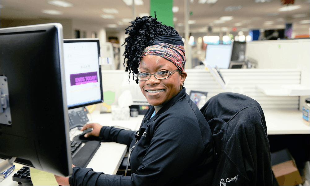 Smiling Care Coordinator at her desk with monitors 