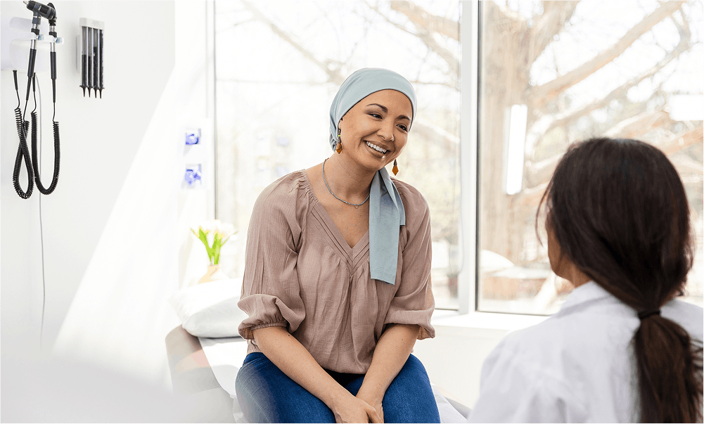 Smiling cancer patient talks with doctor in office