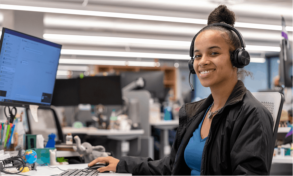 woman wearing headset in front of computer and smiling at camera