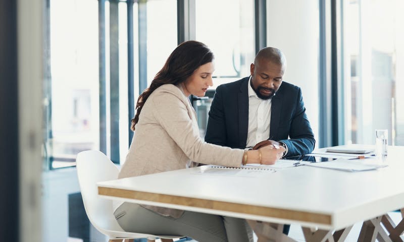 male and female coworkers at a table looking at financials