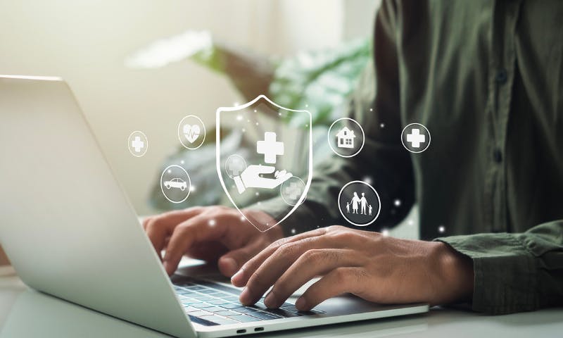 Hands type on laptop with medical illustrations