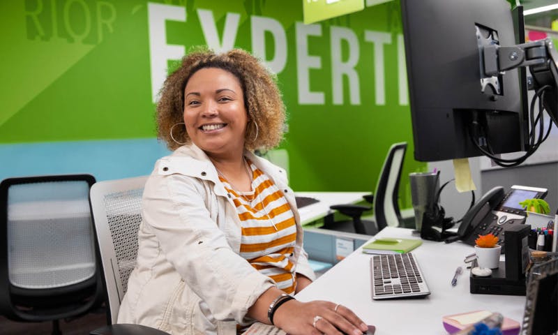 quantum health employee smiling at camera in front of computer