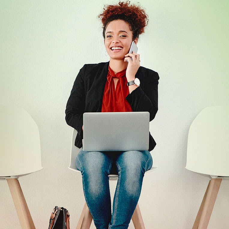 Lady on laptop while on the phone smiling