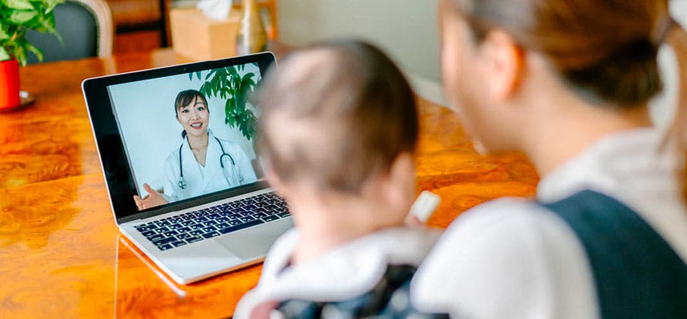 a woman and her baby connecting with their doctor virtually. 