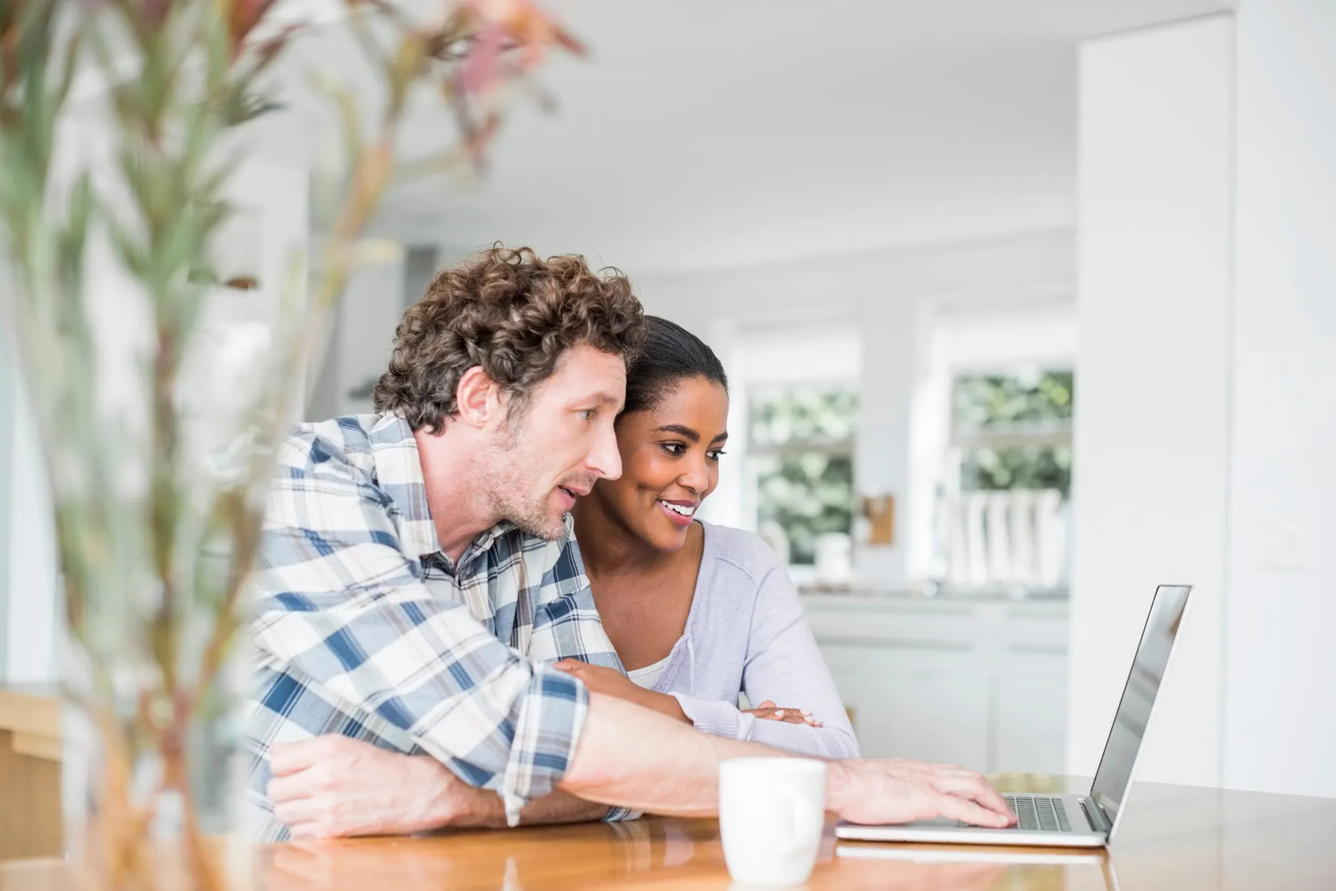Man and woman looking at laptop at kitchen table