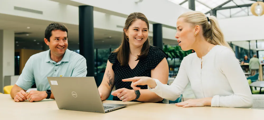 Three people meeting in front of a laptop