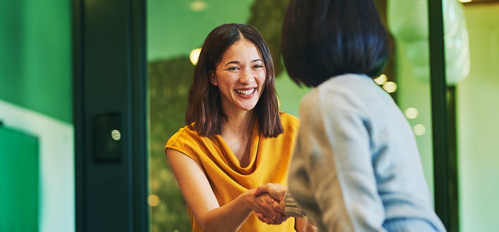Two coworkers shaking hands and smiling.