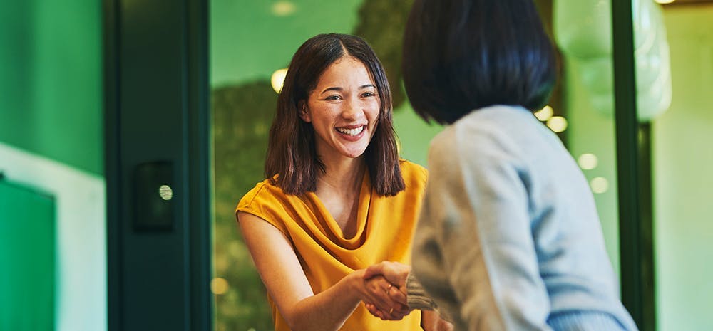 Two coworkers shaking hands and smiling.