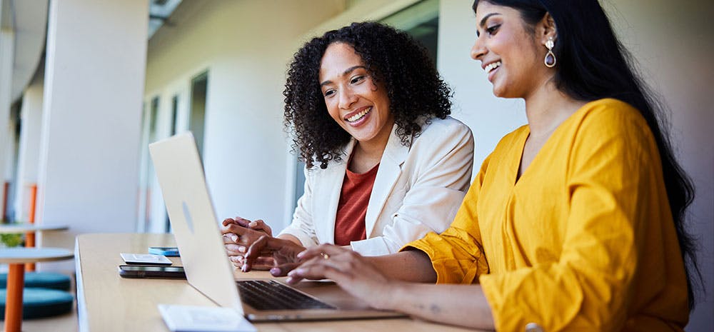 Woman coworkers smiling at computer together