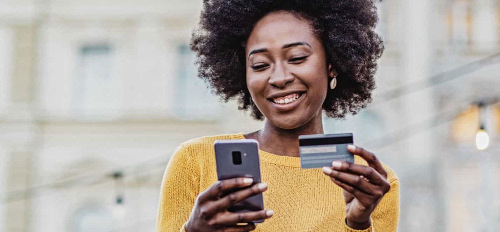 Woman smiling with her phone and credit card