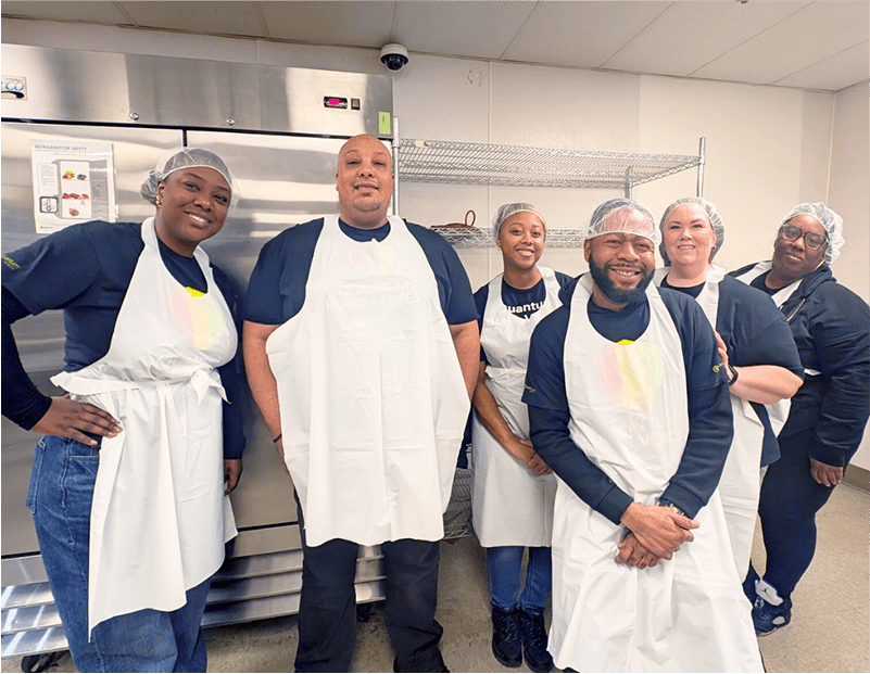 six people wearing hairnets and aprons during a volunteer event