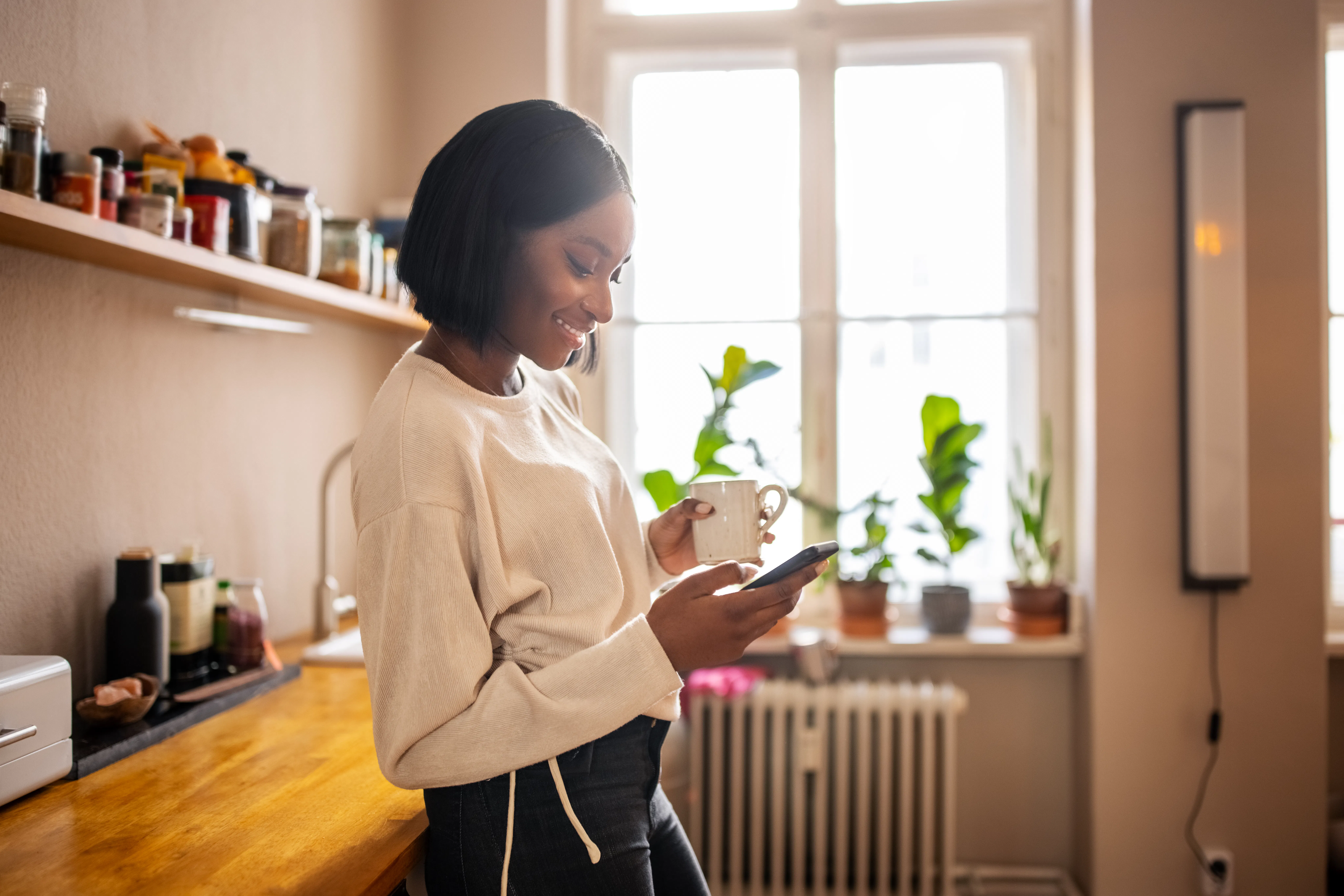 Woman in kitchen smiling on phone