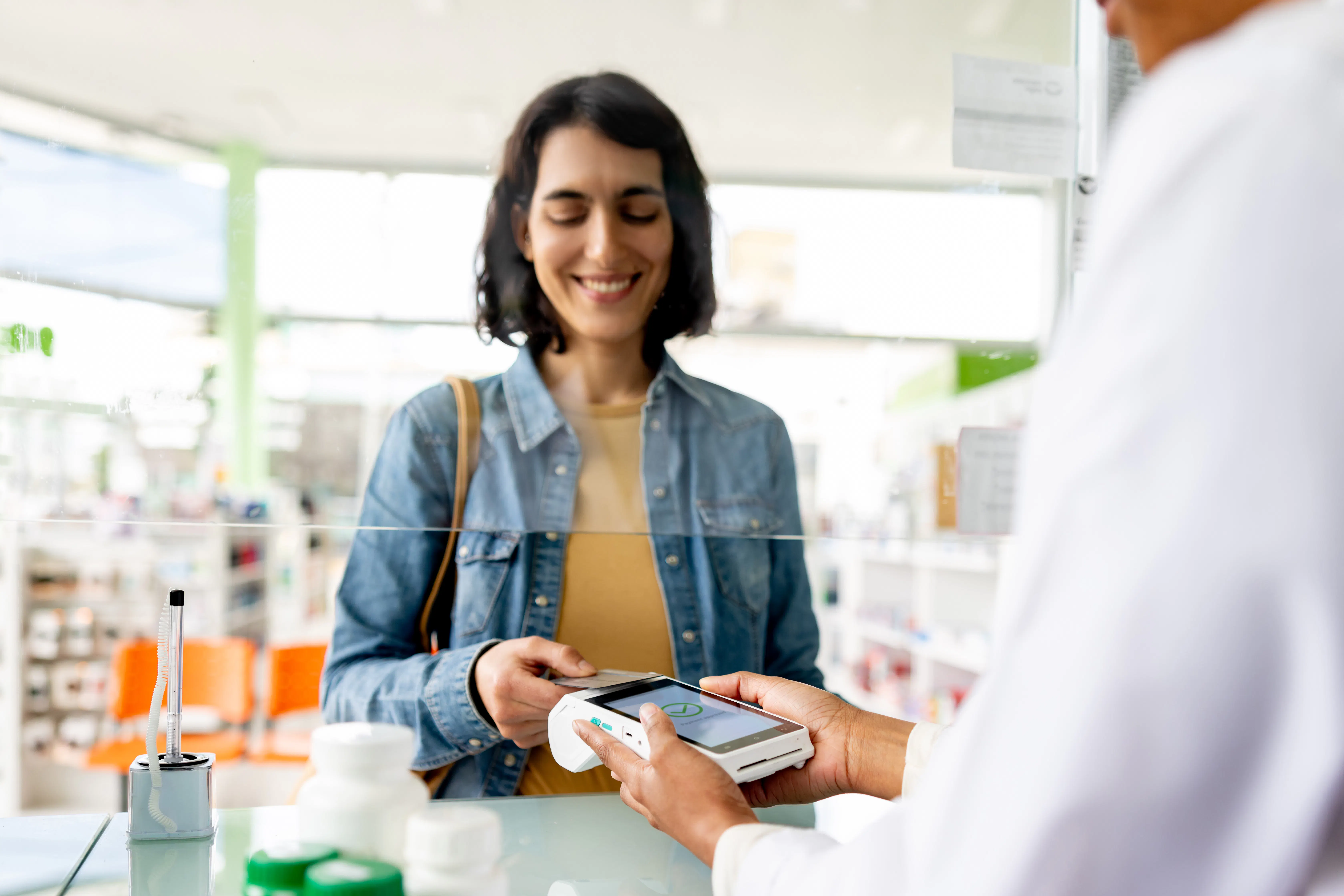 Woman tapping payment card at pharmacy