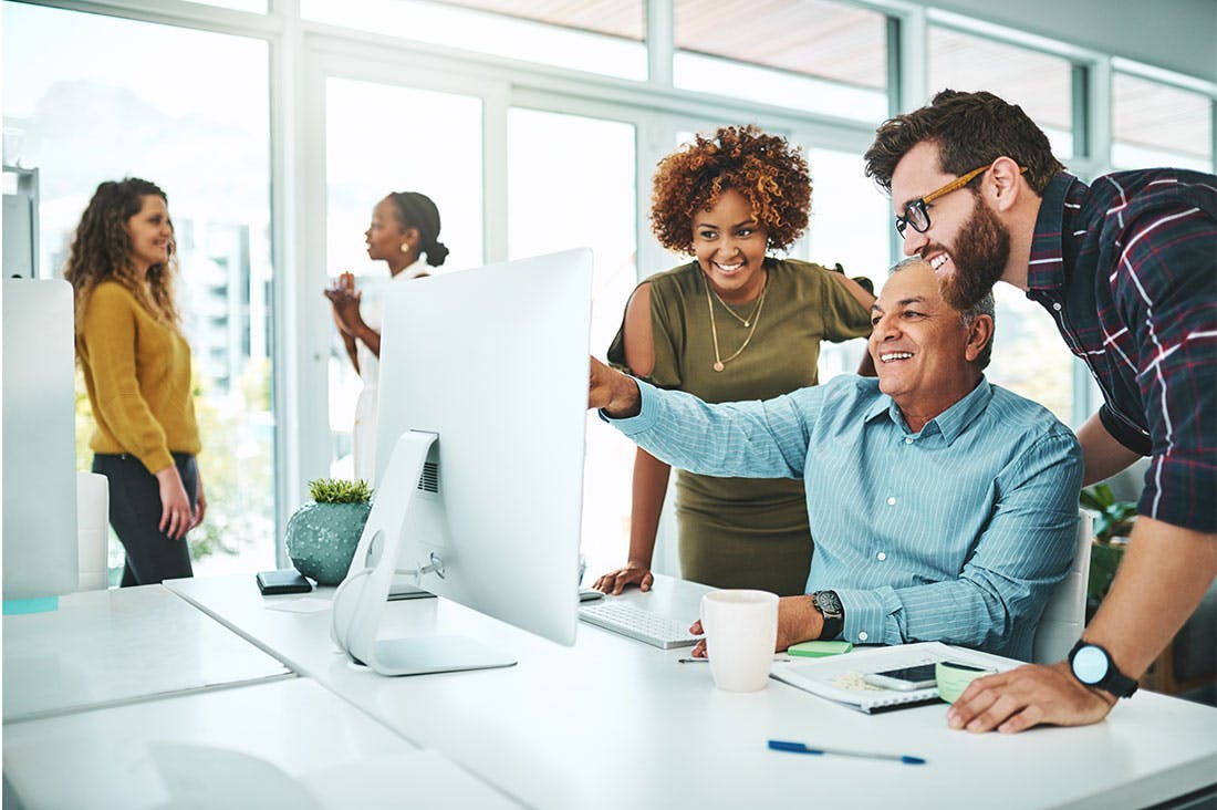 Diverse coworkers working together around a monitor