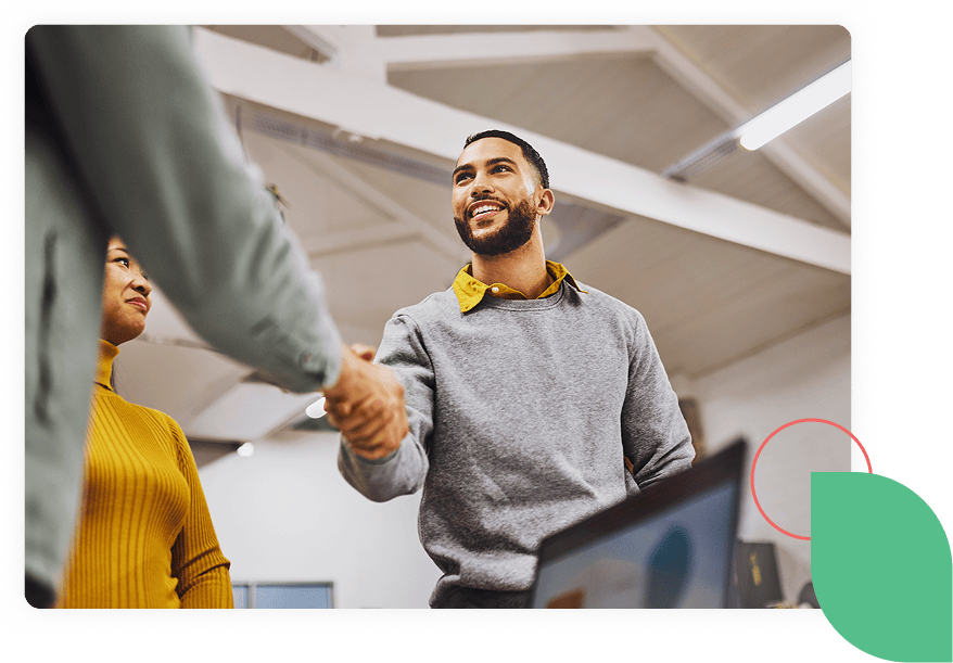 Smiling man shakes hands with an off camera person with an image decoration in the bottom right hand corner