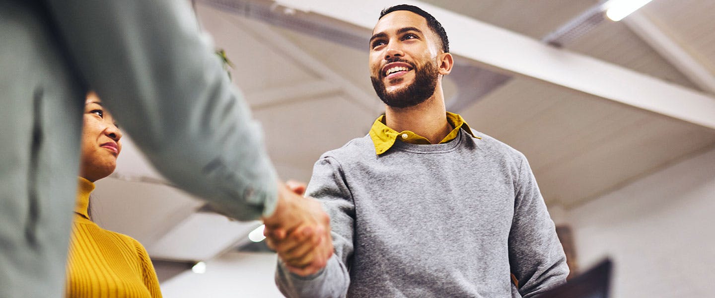 Man smiling and shaking coworkers hand