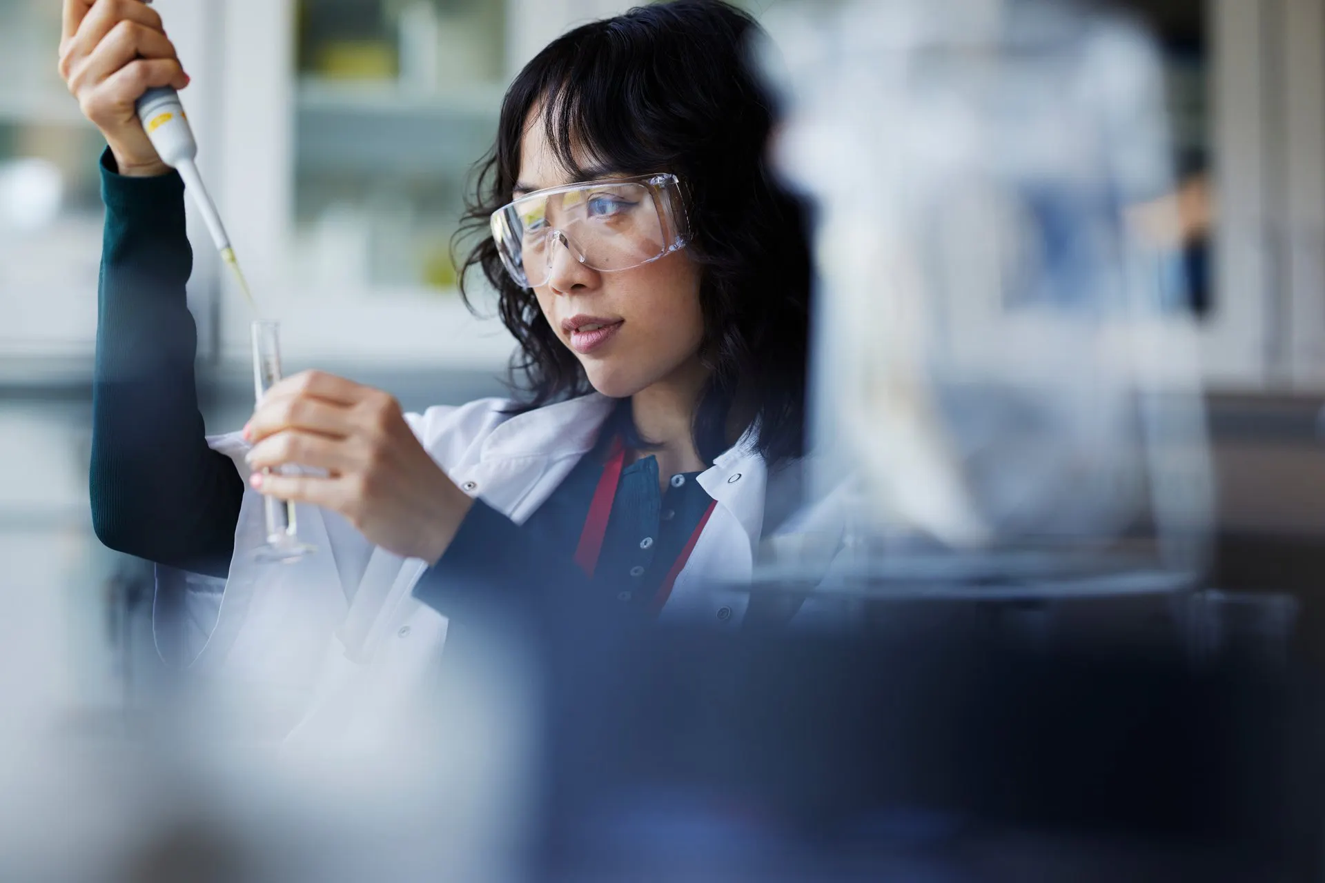 A woman in a lab coat holding a pipette and a test tube.