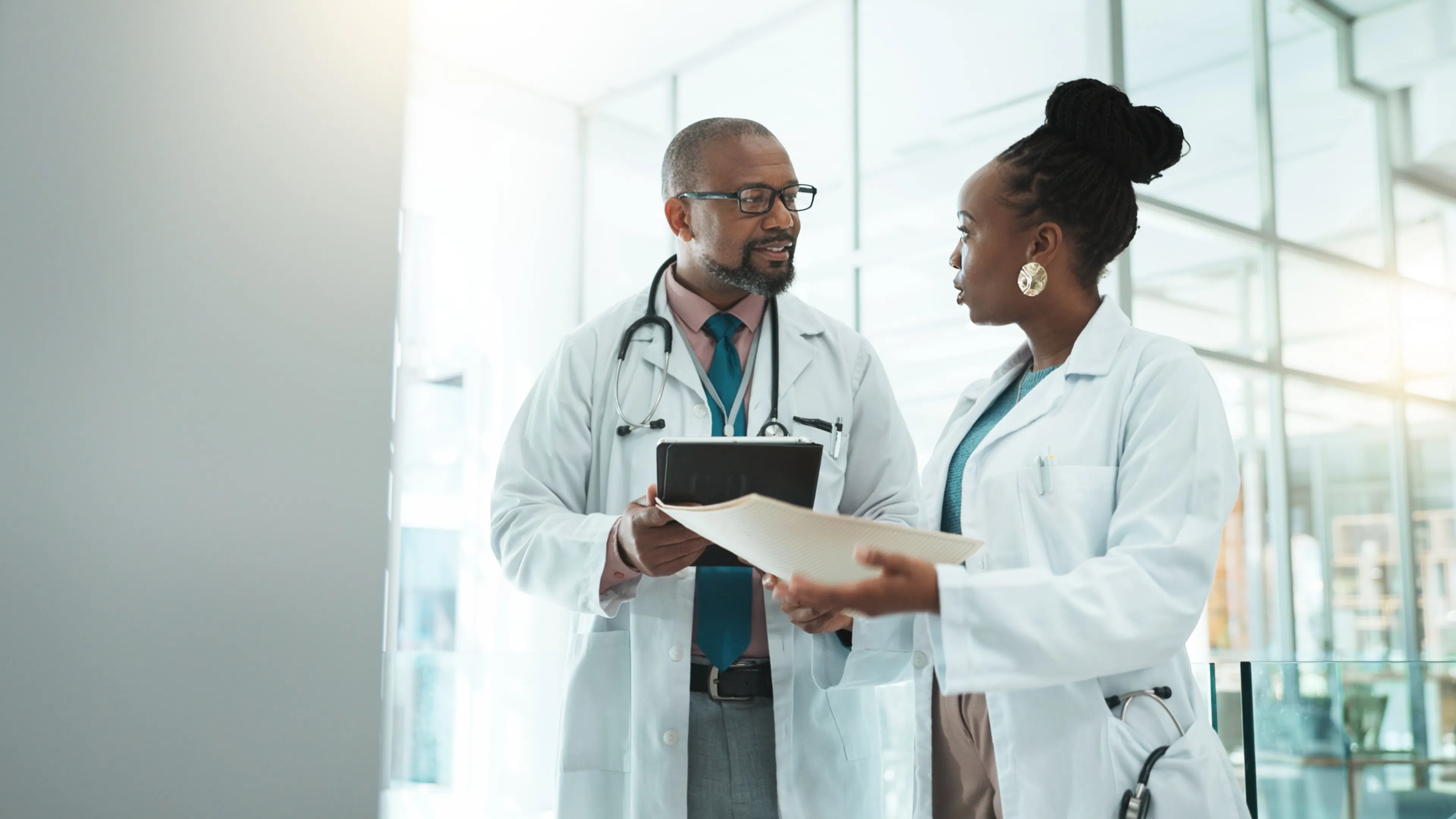 Two doctors in white coats discussing a document in a medical office.