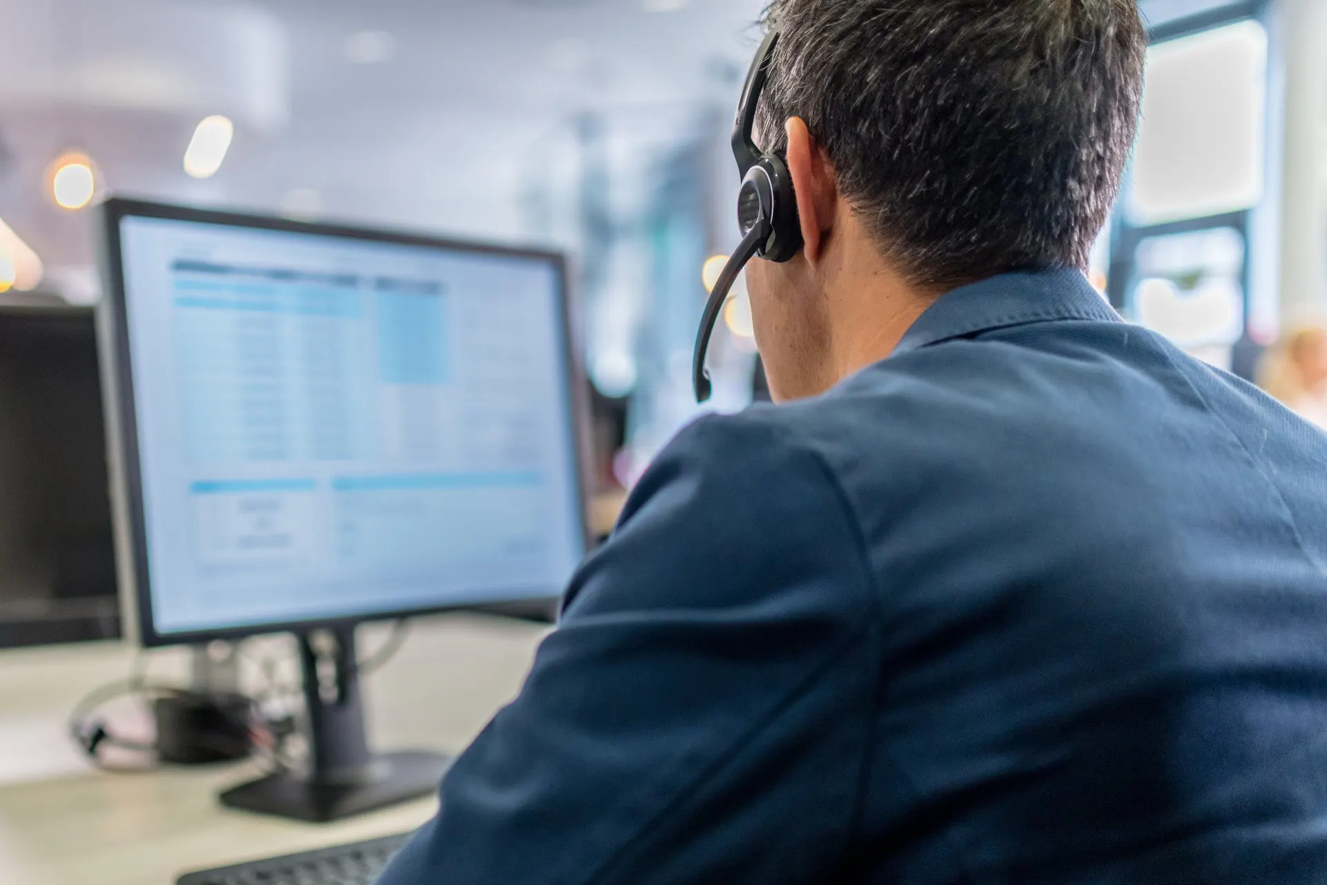 Rear view of man wearing headset in front of computer