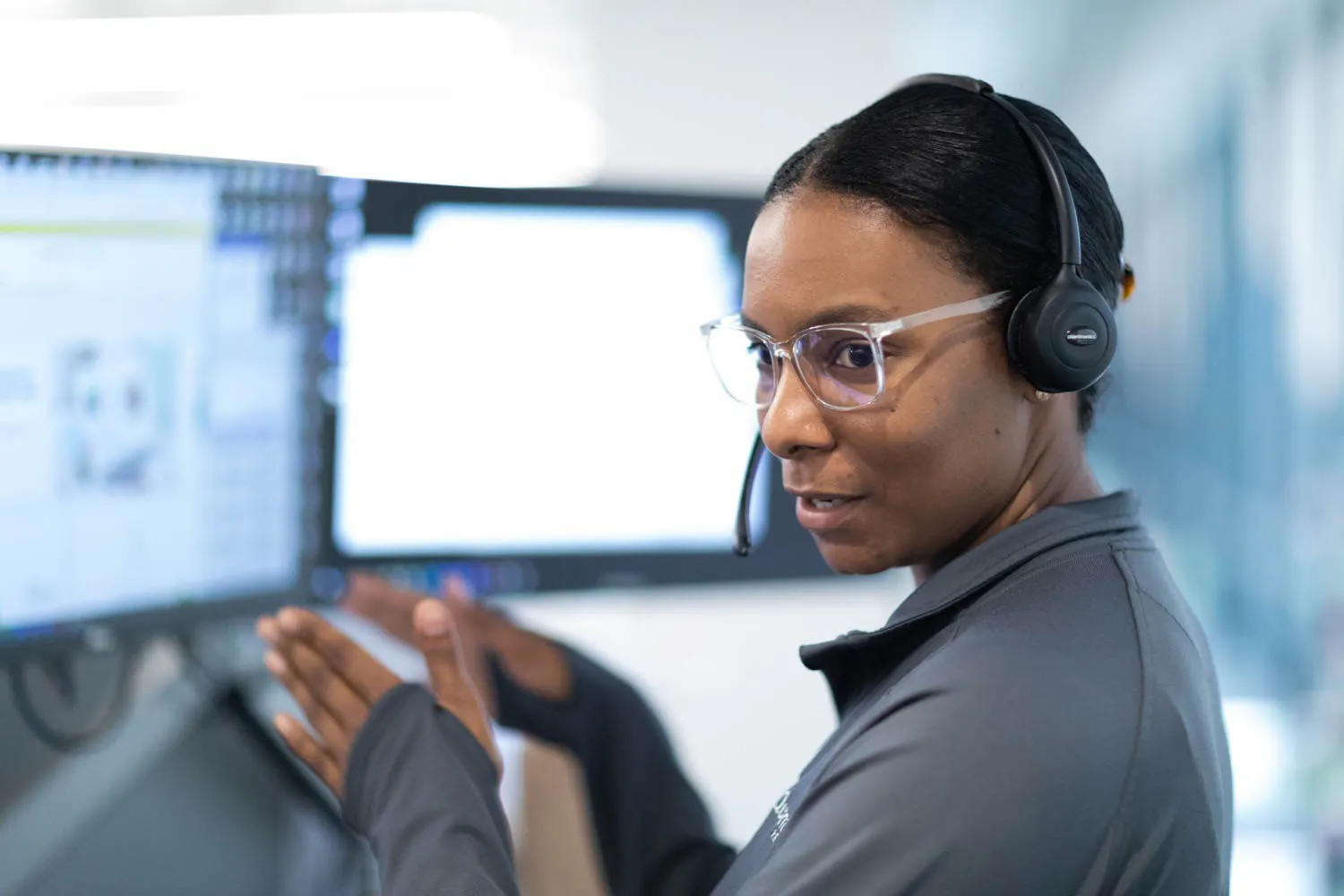 A black woman looking away and gesturing to her computer.