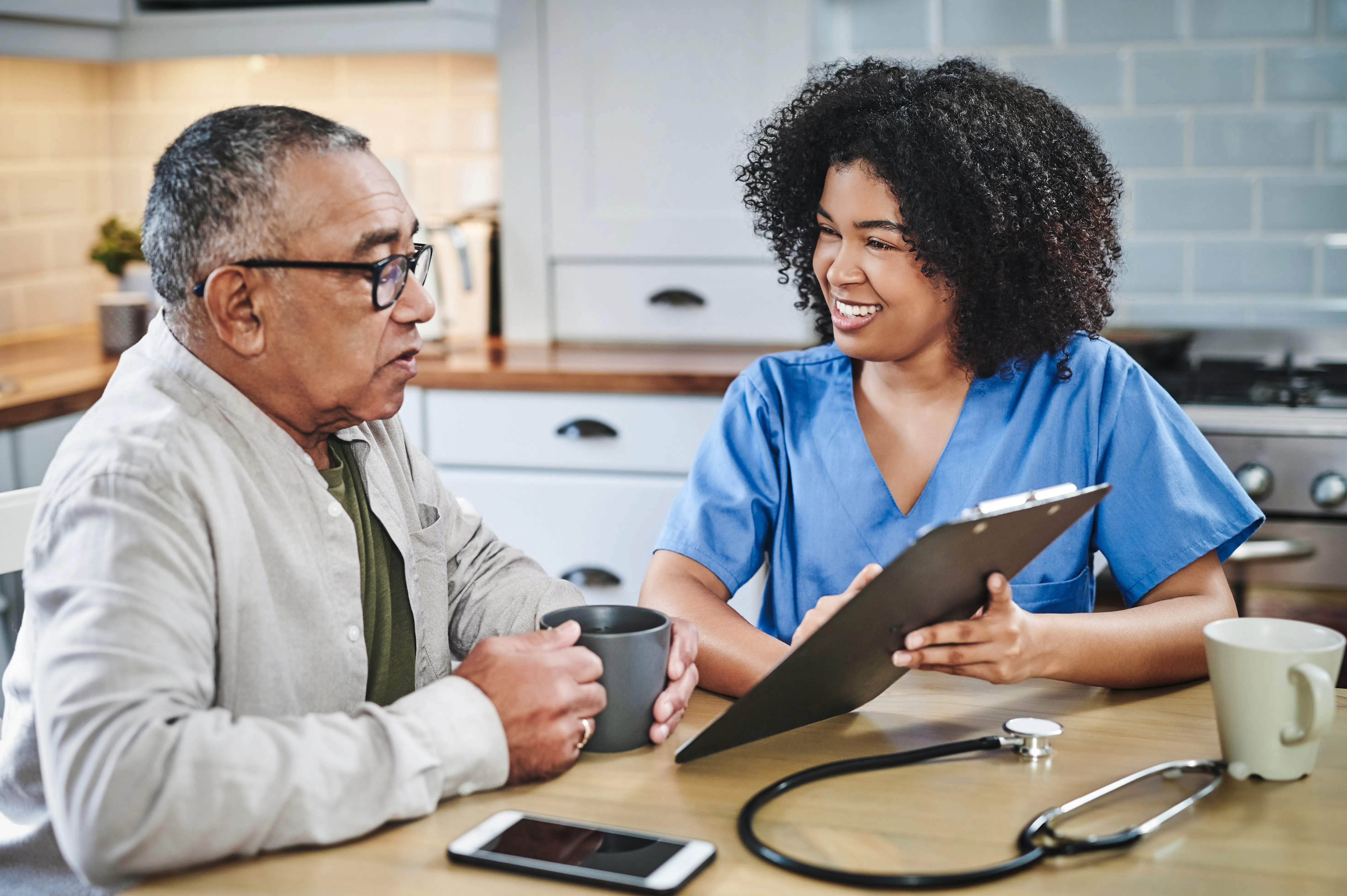 Nurse sitting with elderly patient and using a clipboard