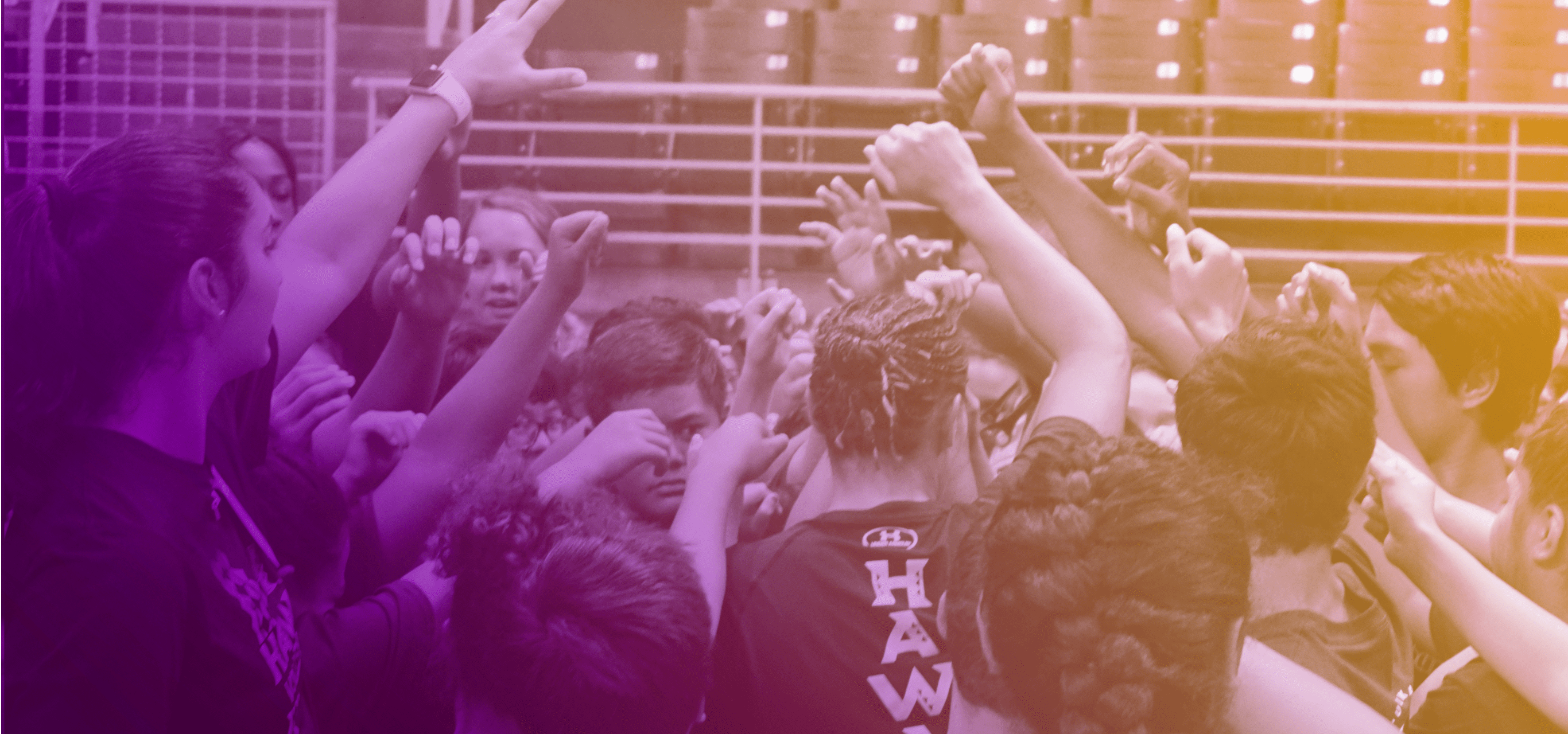 A group of children in sport attire raising their hands